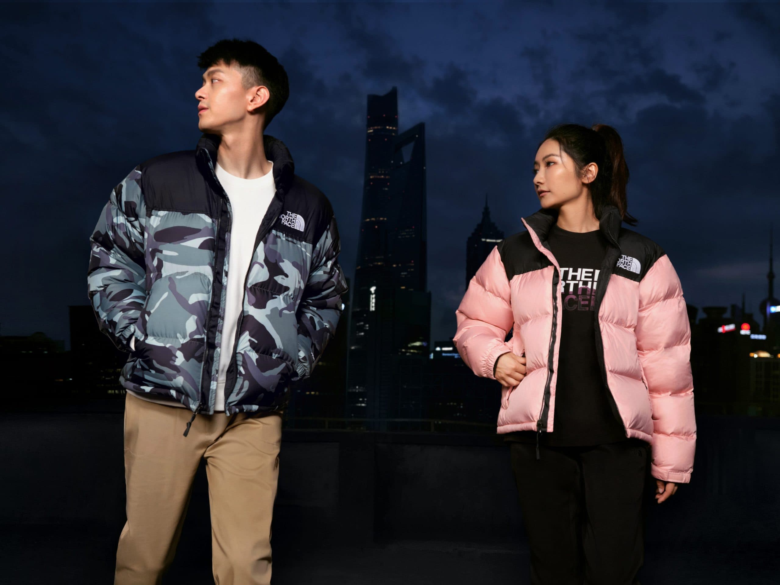 Две модели в пуховиках The North Face Nuptse на фоне вечернего города